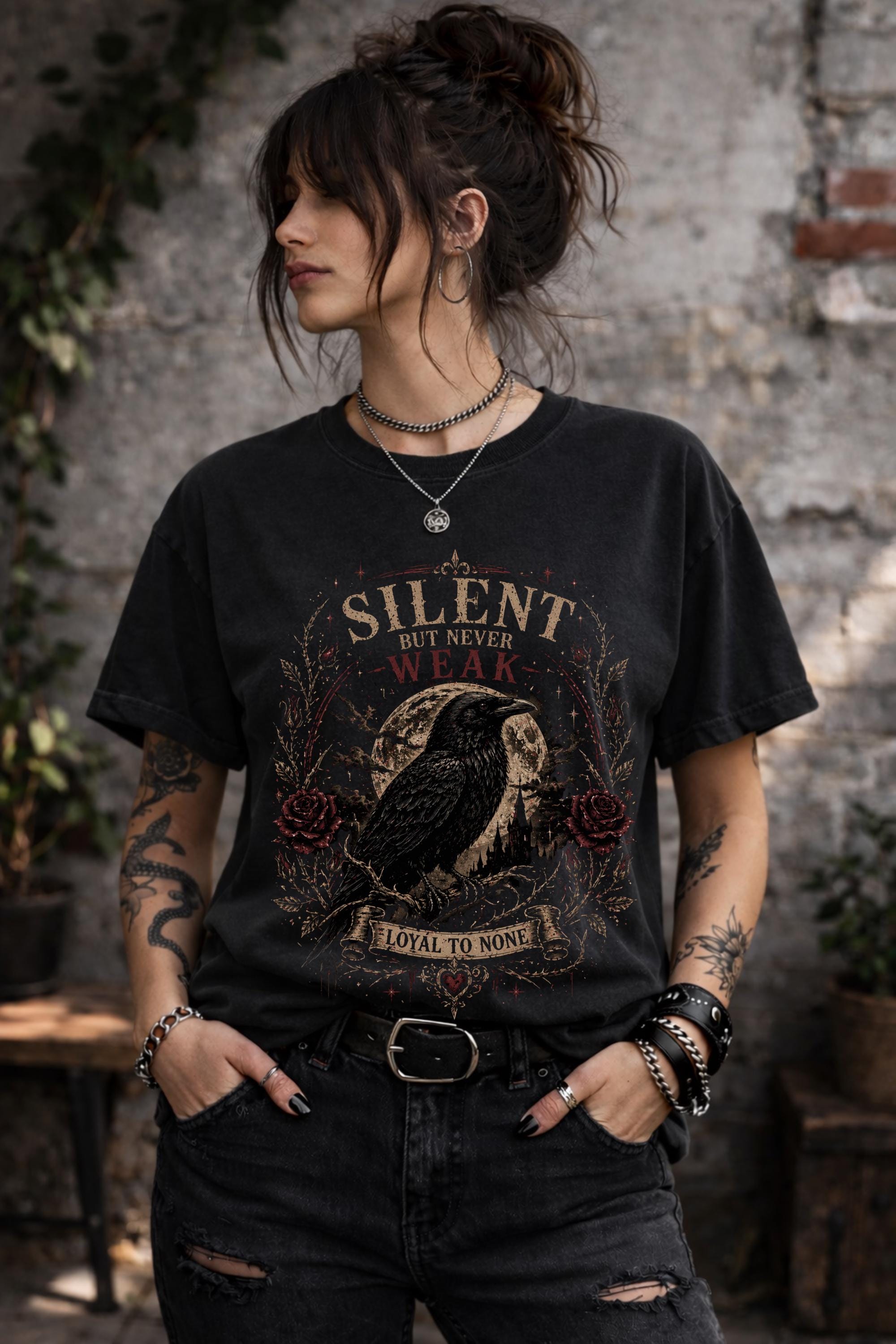 Gothic raven t-shirt with “Silent But Never Weak” design worn by woman in black tee, dark academia aesthetic outfit with edgy style