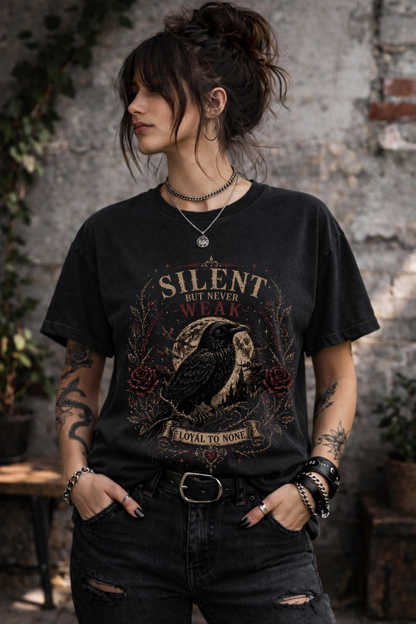 Gothic raven t-shirt with “Silent But Never Weak” design worn by woman in black tee, dark academia aesthetic outfit with edgy style