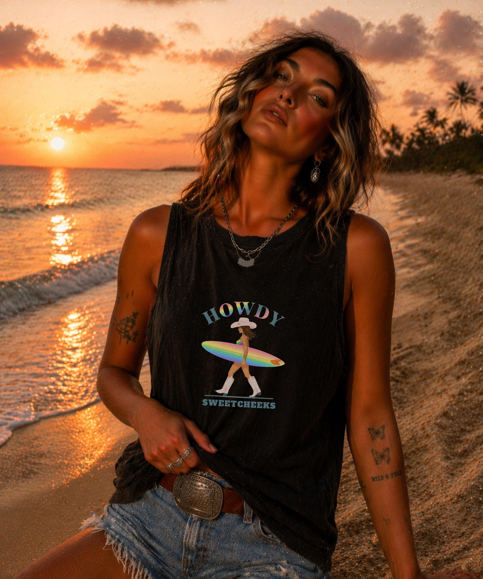 Female model in garment dyed tank top with rainbow cowgirl surfer graphic, coastal beach scene, golden hour lighting