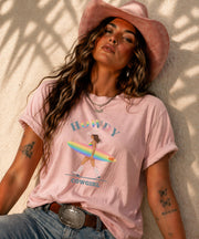 Woman wearing Comfort Colors Tshirt with Howdy Cowgirl rainbow surf design, beach sunset background, boho western outfit