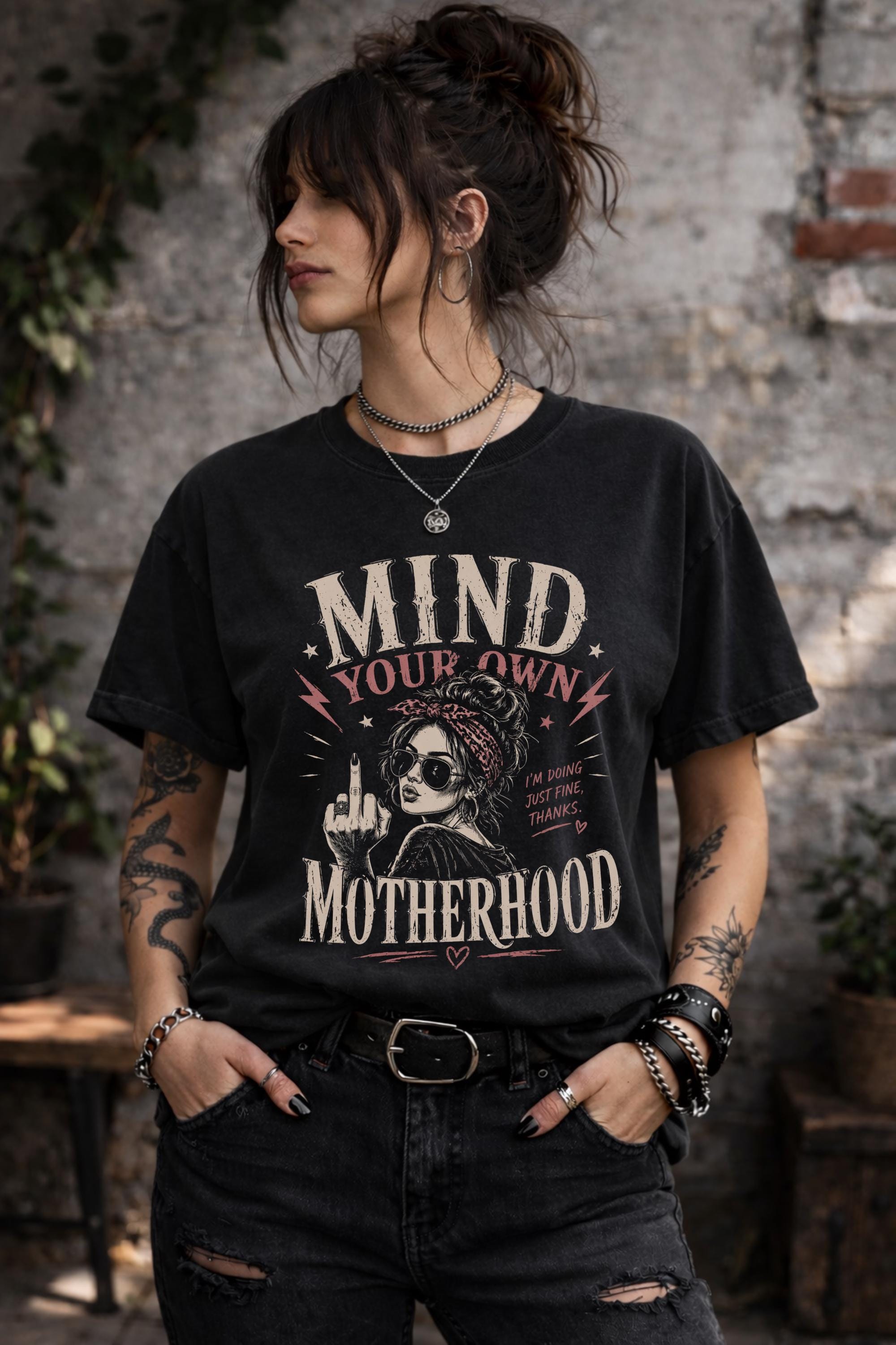 Woman wearing black motherhood graphic t-shirt with mind your own motherhood slogan outdoors