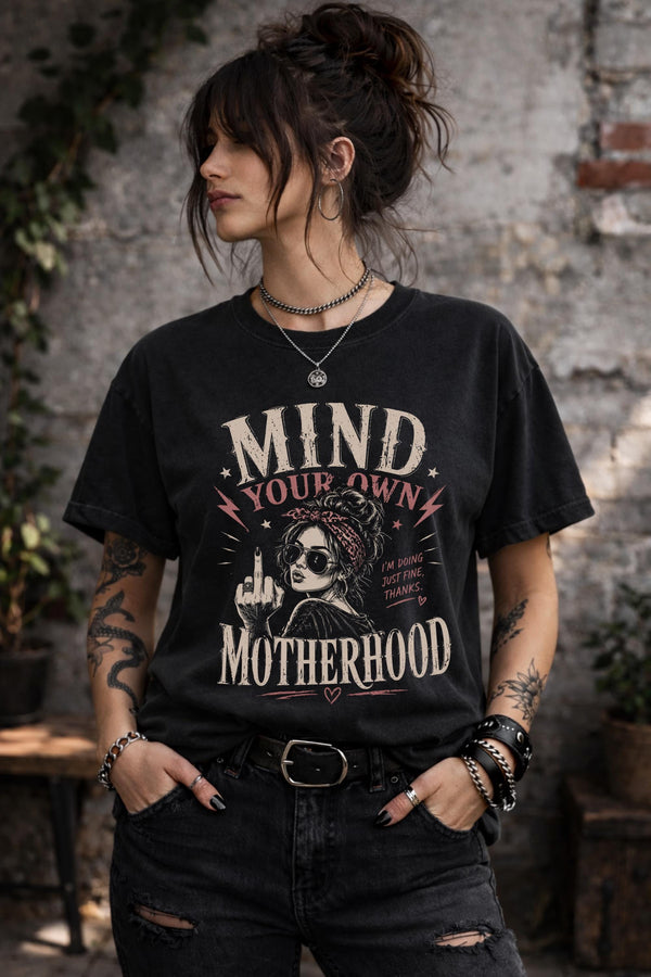 Woman wearing black motherhood graphic t-shirt with mind your own motherhood slogan outdoors