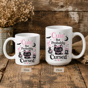White ceramic mug featuring Cute But Probably Cursed gothic cat design in pink and black on rustic background