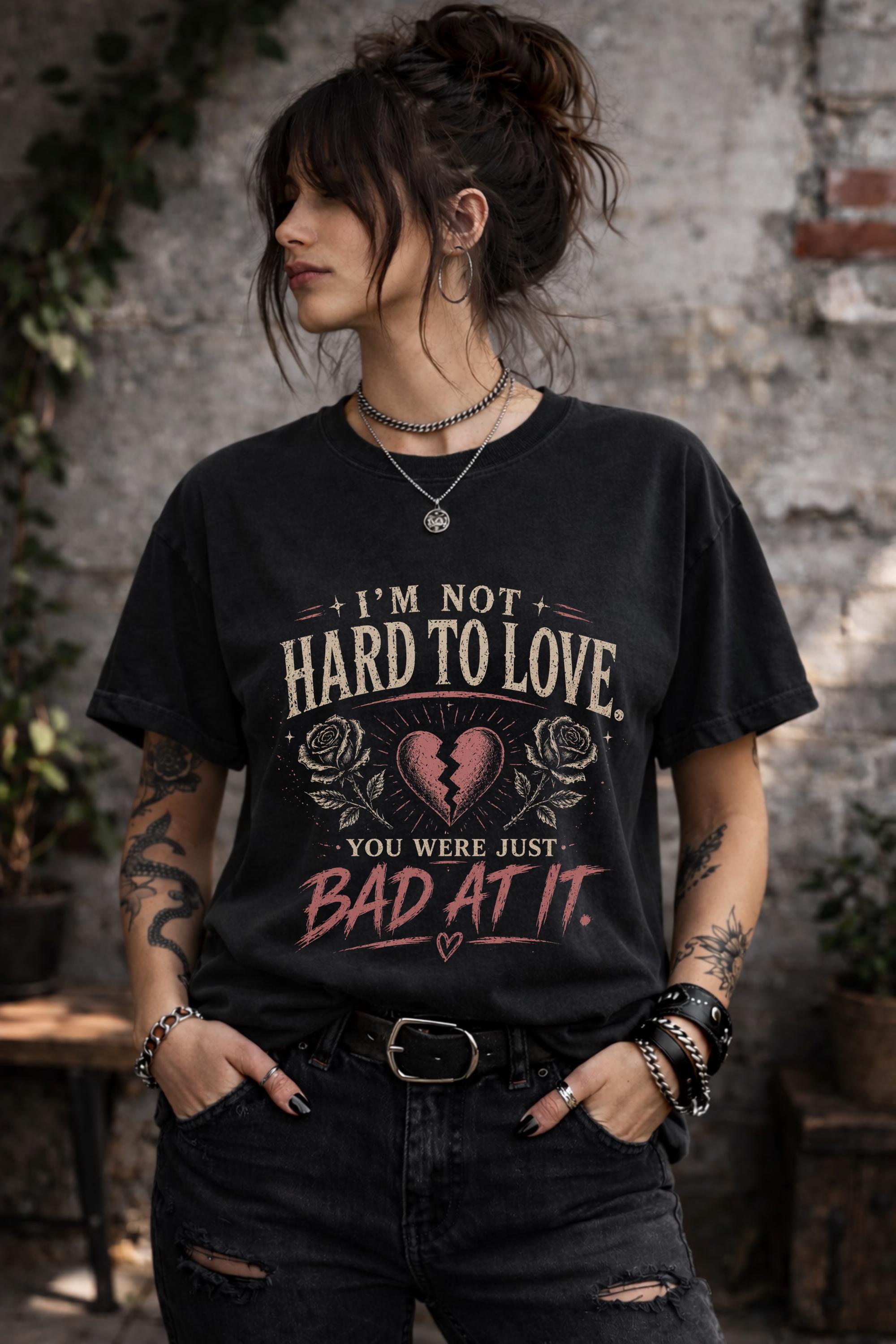 Woman wearing navy graphic t-shirt with sarcastic breakup quote I’m Not Hard to Love You Were Just Bad At It with broken heart design