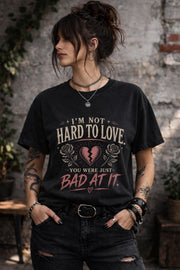 Woman wearing navy graphic t-shirt with sarcastic breakup quote I’m Not Hard to Love You Were Just Bad At It with broken heart design