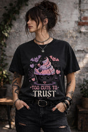 Woman wearing a graphic t-shirt featuring spooky kawaii cupcake with bats hearts spiderwebs and Too Cute to Trust quote