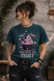 Woman wearing a graphic t-shirt featuring spooky kawaii cupcake with bats hearts spiderwebs and Too Cute to Trust quote