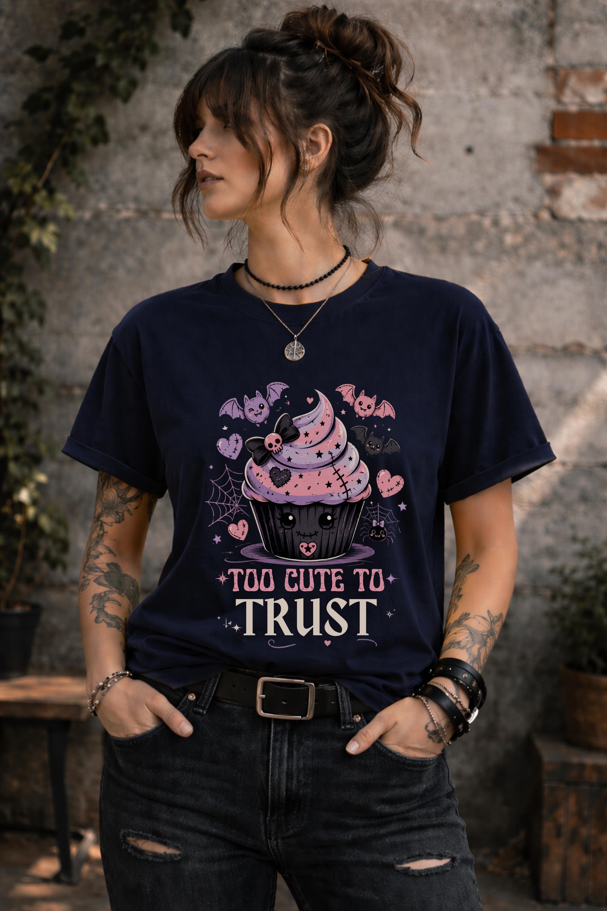 Woman wearing a graphic t-shirt featuring spooky kawaii cupcake with bats hearts spiderwebs and Too Cute to Trust quote