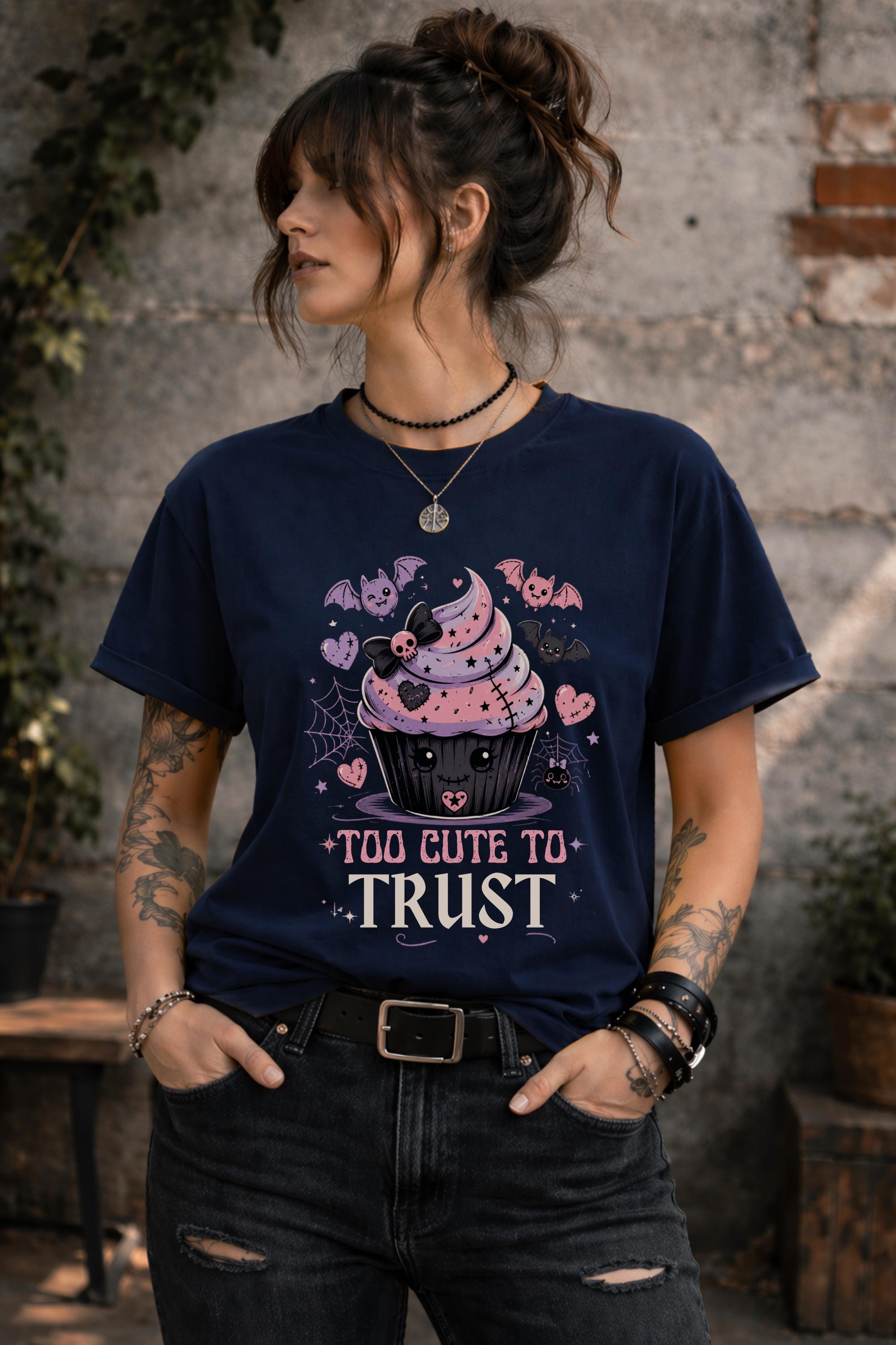 Woman wearing navy graphic t-shirt featuring spooky kawaii cupcake with bats hearts spiderwebs and Too Cute to Trust quote