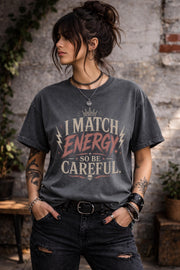 Woman wearing dark vintage wash graphic t-shirt featuring the phrase I Match Energy So Be Careful in distressed typography