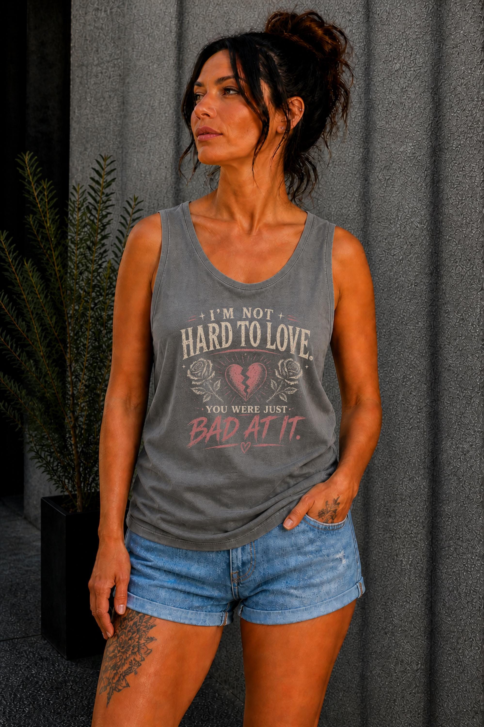 Woman wearing a graphic tank top with sarcastic breakup quote I’m Not Hard to Love You Were Just Bad At It with broken heart design