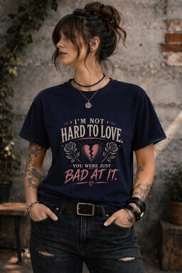 Woman wearing navy graphic t-shirt with sarcastic breakup quote I’m Not Hard to Love You Were Just Bad At It with broken heart design