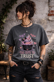 Woman wearing a graphic t-shirt featuring spooky kawaii cupcake with bats hearts spiderwebs and Too Cute to Trust quote