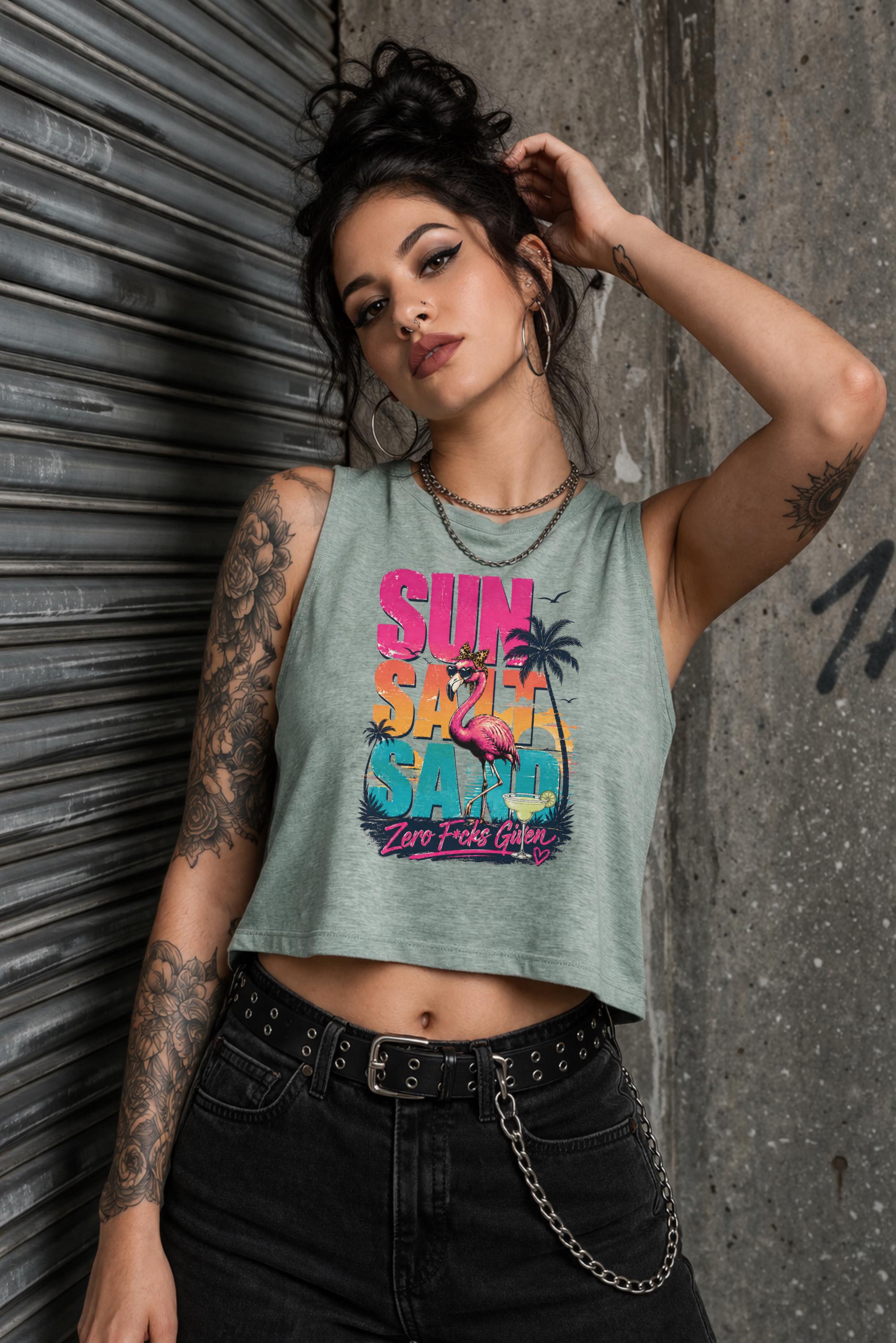 Woman modeling crop tank top featuring colorful retro flamingo graphic with Sun Sand Salad Zero Fcks Given summer vacation design against urban industrial background.