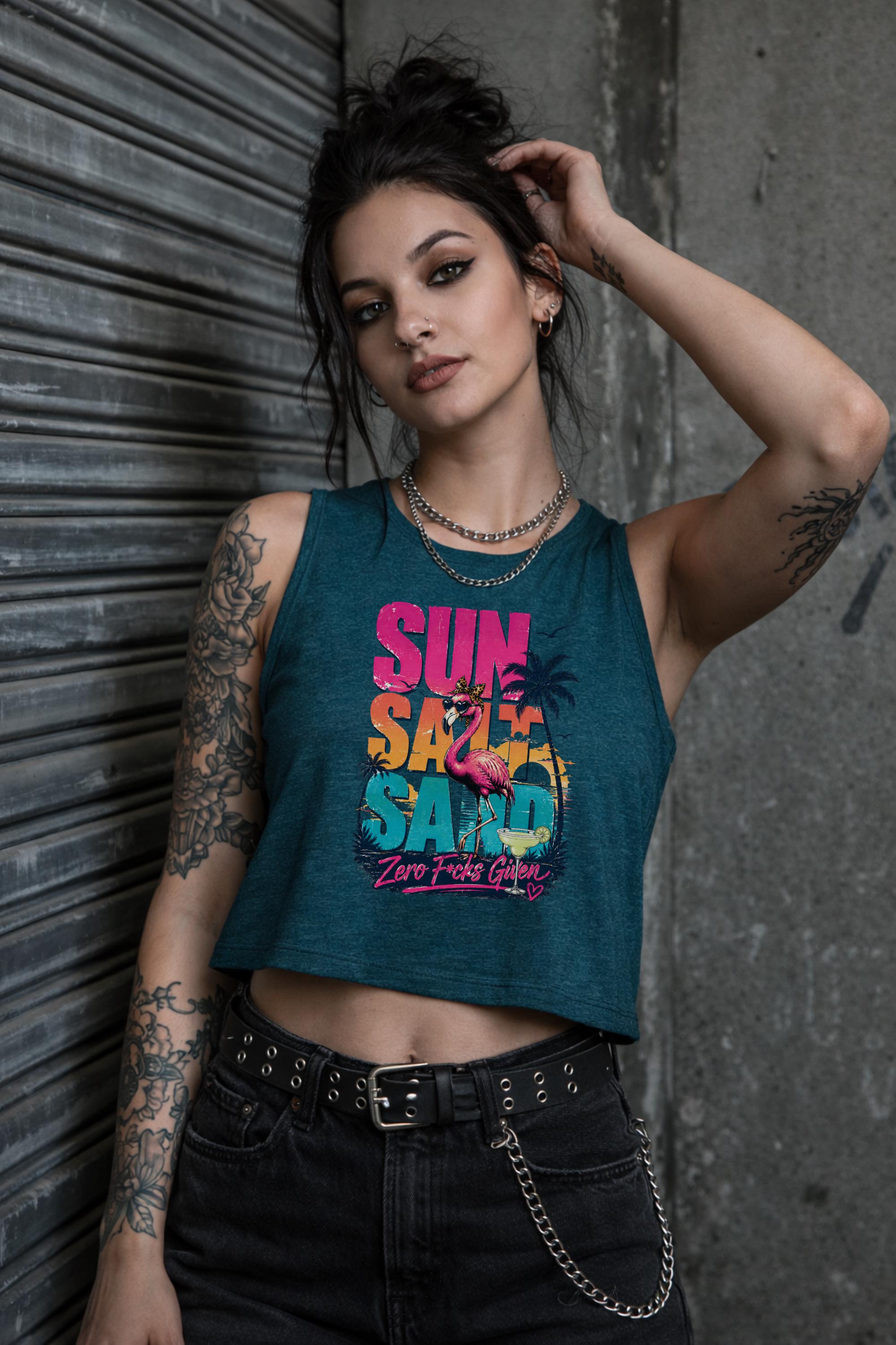 Woman modeling crop tank top featuring colorful retro flamingo graphic with Sun Sand Salad Zero Fcks Given summer vacation design against urban industrial background.