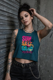 Woman modeling crop tank top featuring colorful retro flamingo graphic with Sun Sand Salad Zero Fcks Given summer vacation design against urban industrial background.