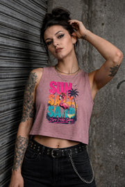 Woman modeling crop tank top featuring colorful retro flamingo graphic with Sun Sand Salad Zero Fcks Given summer vacation design against urban industrial background.