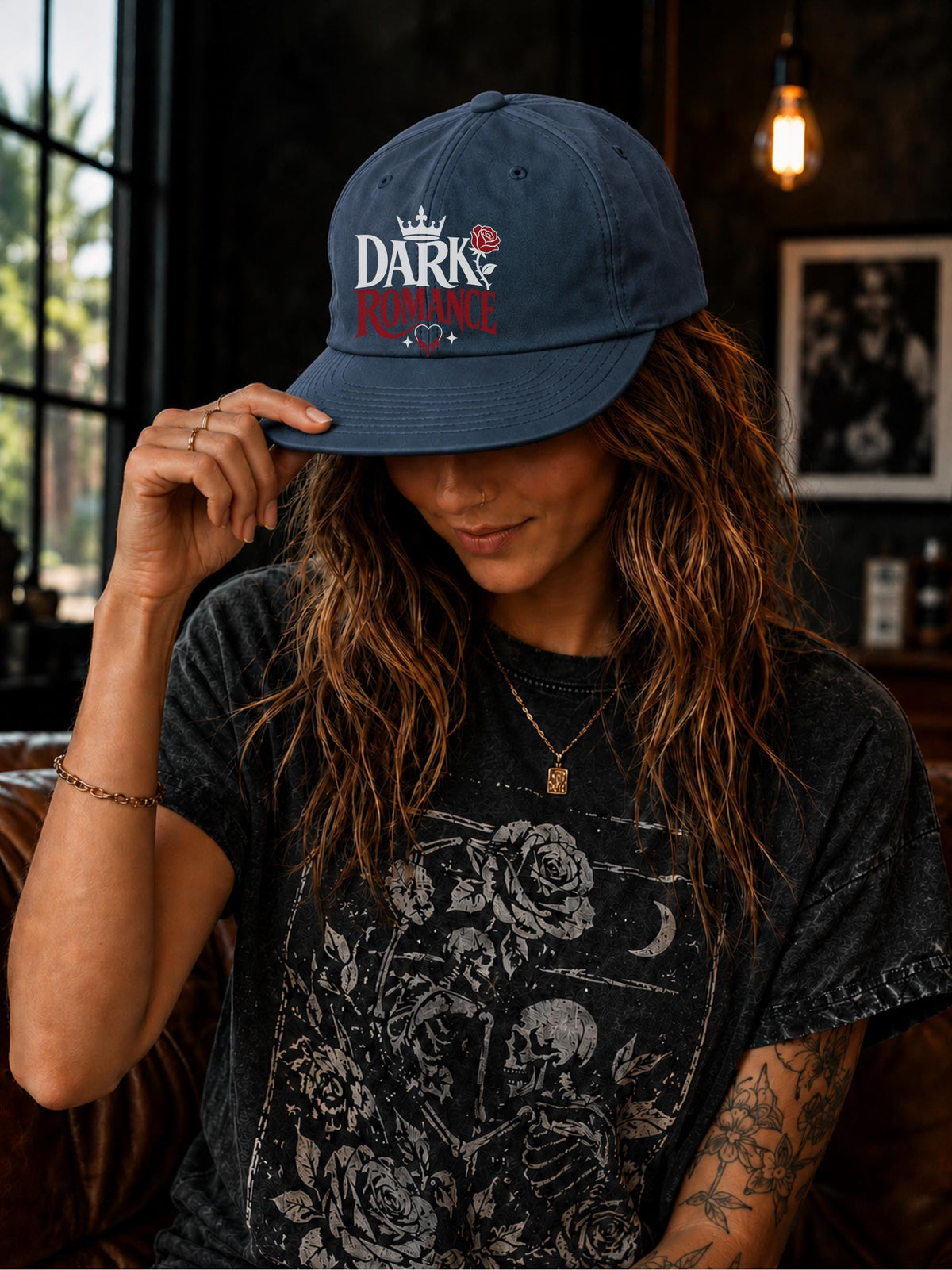 Woman wearing a surf cap featuring a Dark Romance graphic with red rose detail, photographed in a moody bookish setting with dark academia aesthetic.