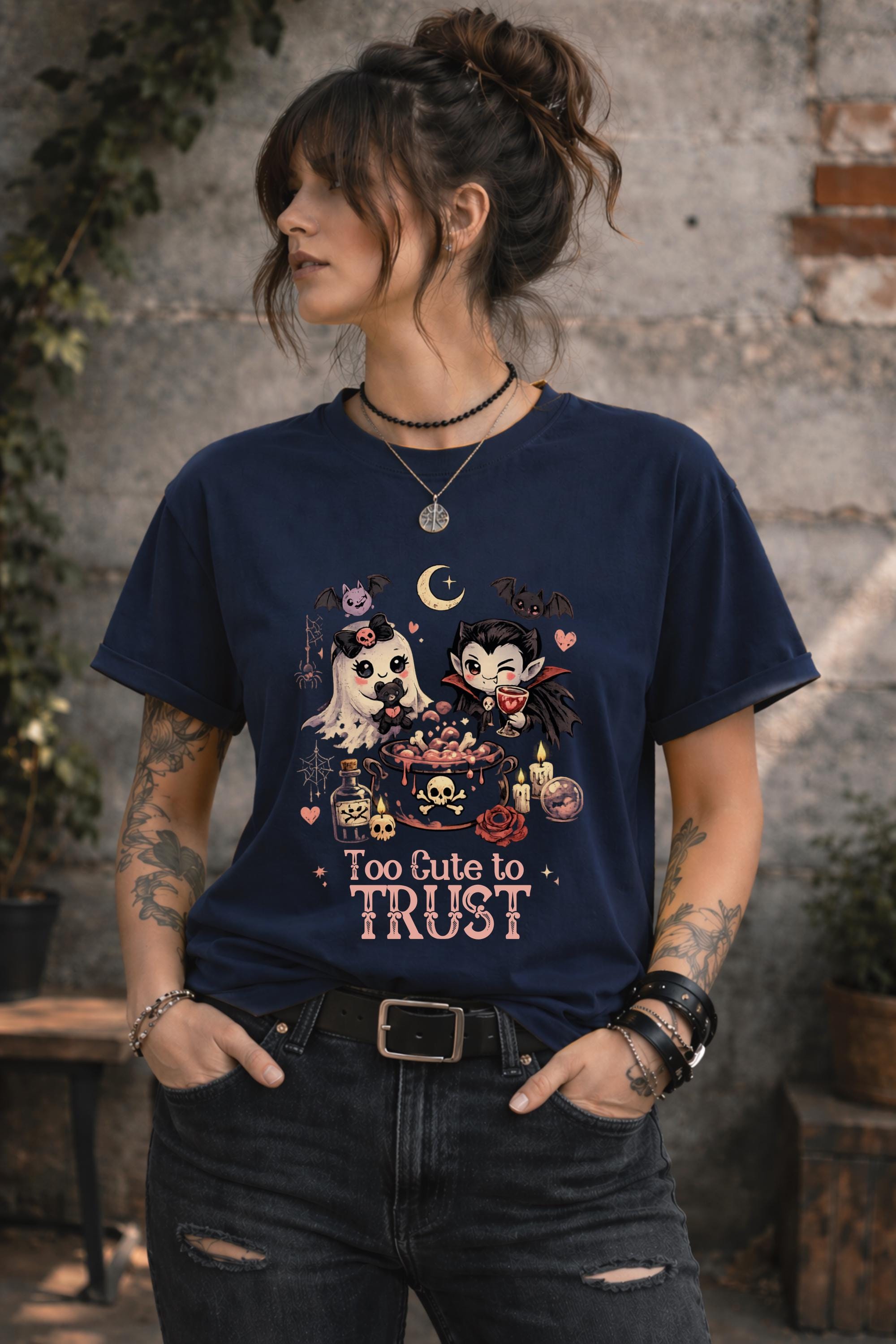 Too Cute To Trust graphic t-shirt featuring adorable ghost, vampire, potion cauldron, bats, candles, skulls, and gothic Halloween artwork.