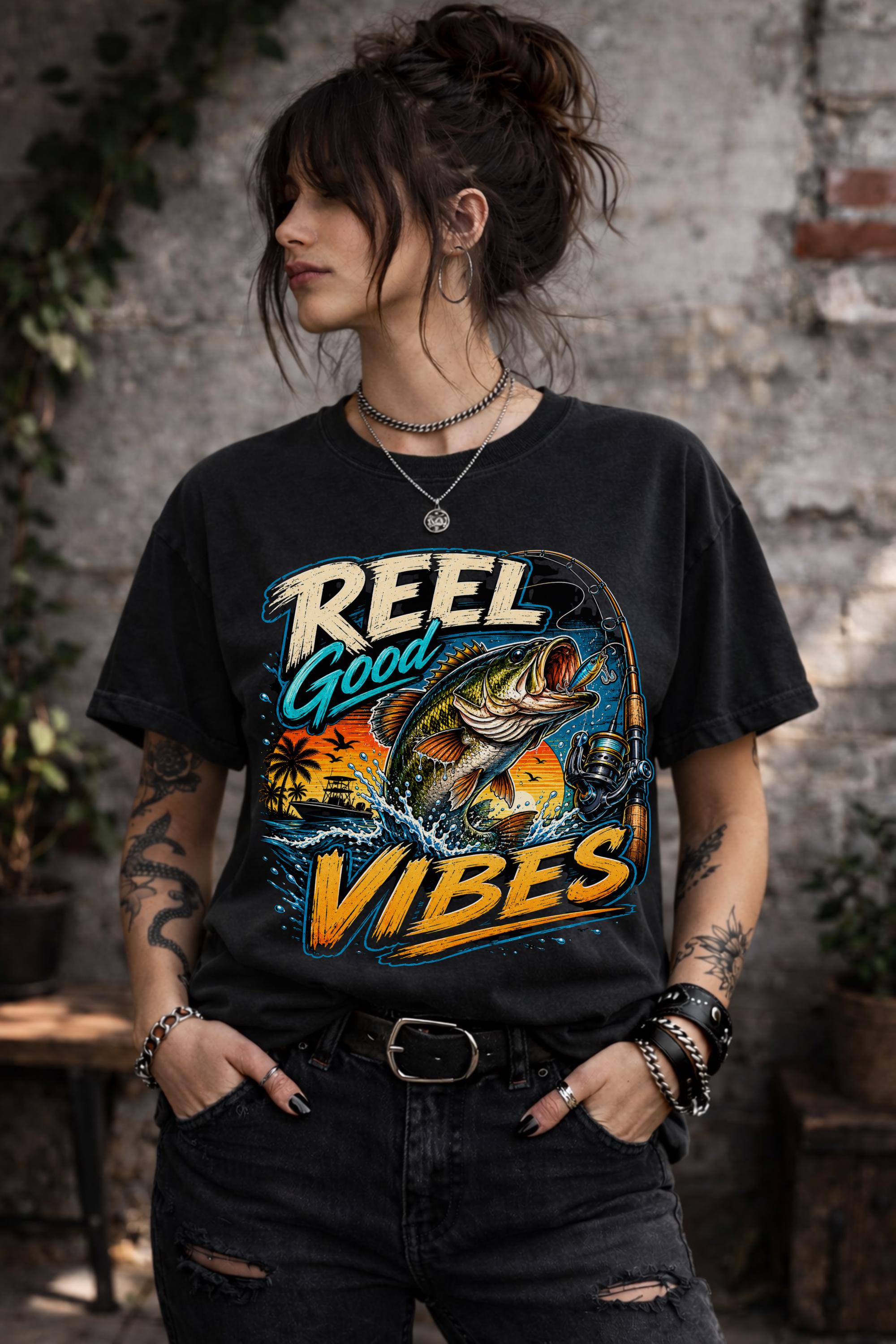 Woman wearing a graphic t-shirt featuring a jumping bass fish, fishing rod, tropical sunset scene, and Reel Good Vibes lettering.