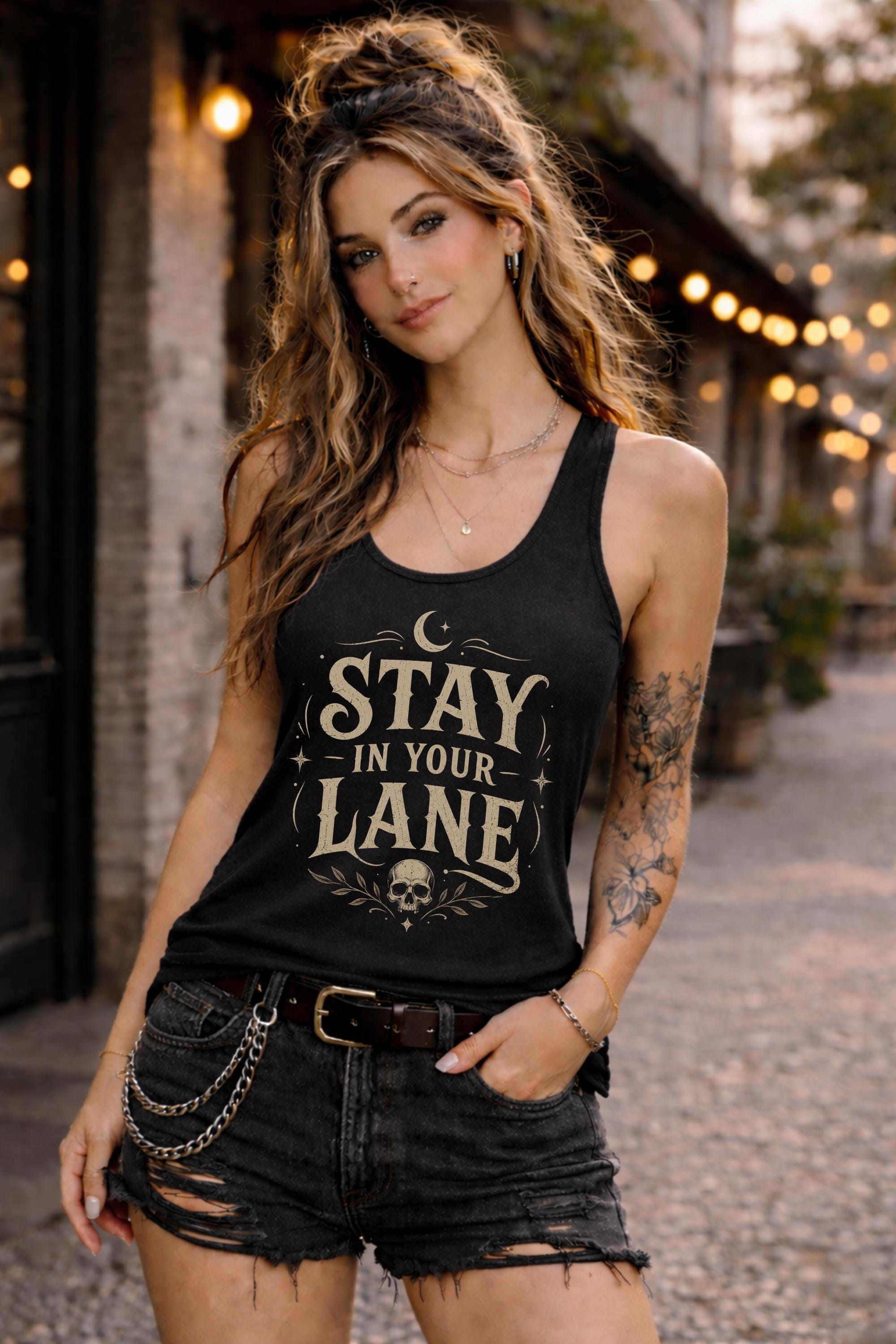 Woman wearing black Stay In Your Lane graphic racerback tank with edgy gothic typography and skull detail