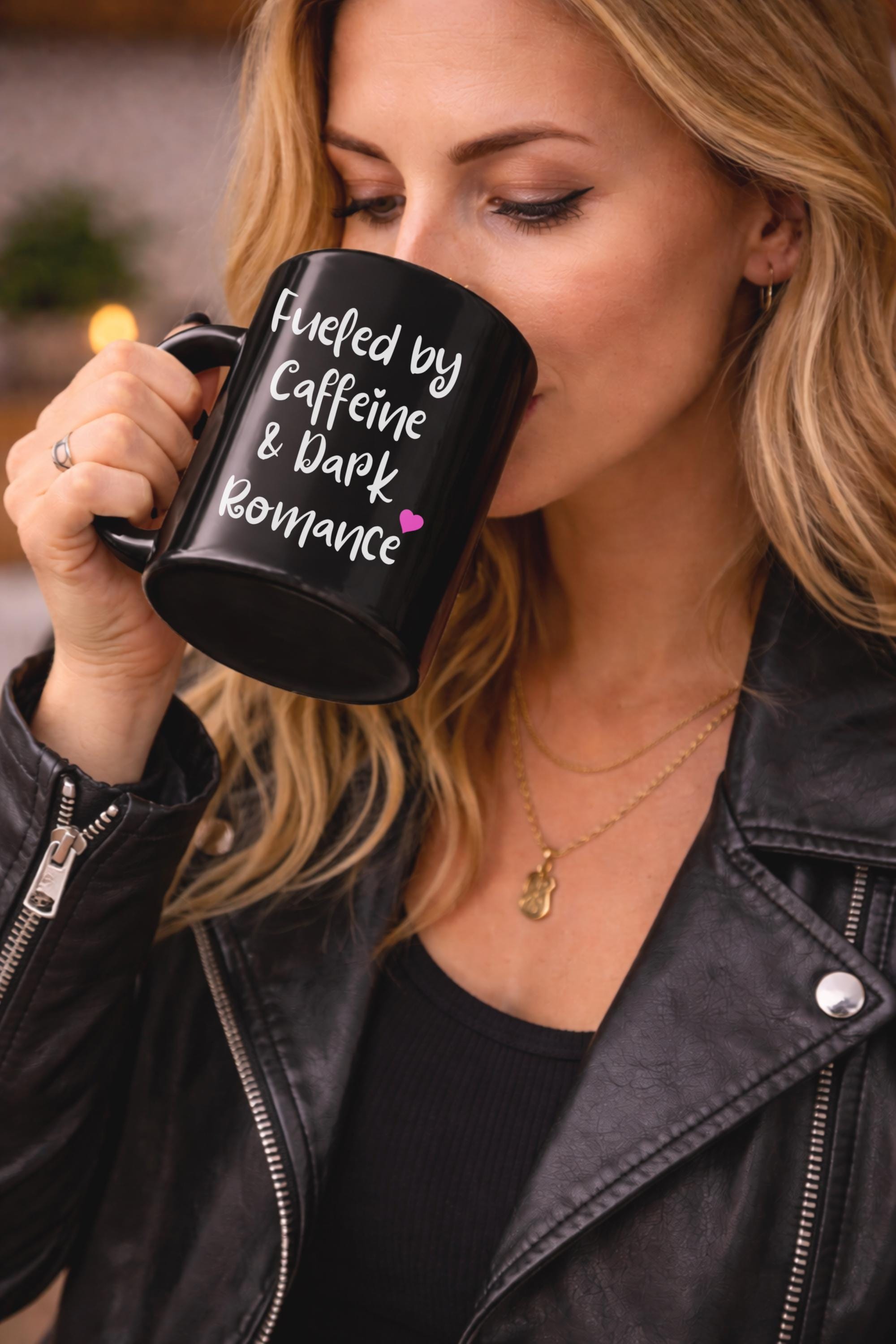 11oz and 15oz black ceramic mugs featuring the phrase "Fueled by Caffeine & Dark Romance" displayed on a rustic wooden table in a cozy kitchen setting.