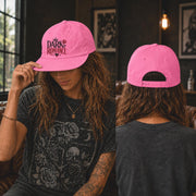 Woman wearing a surf cap featuring a Dark Romance graphic with red rose detail, photographed in a moody bookish setting with dark academia aesthetic. Showing the front and back of the cap.