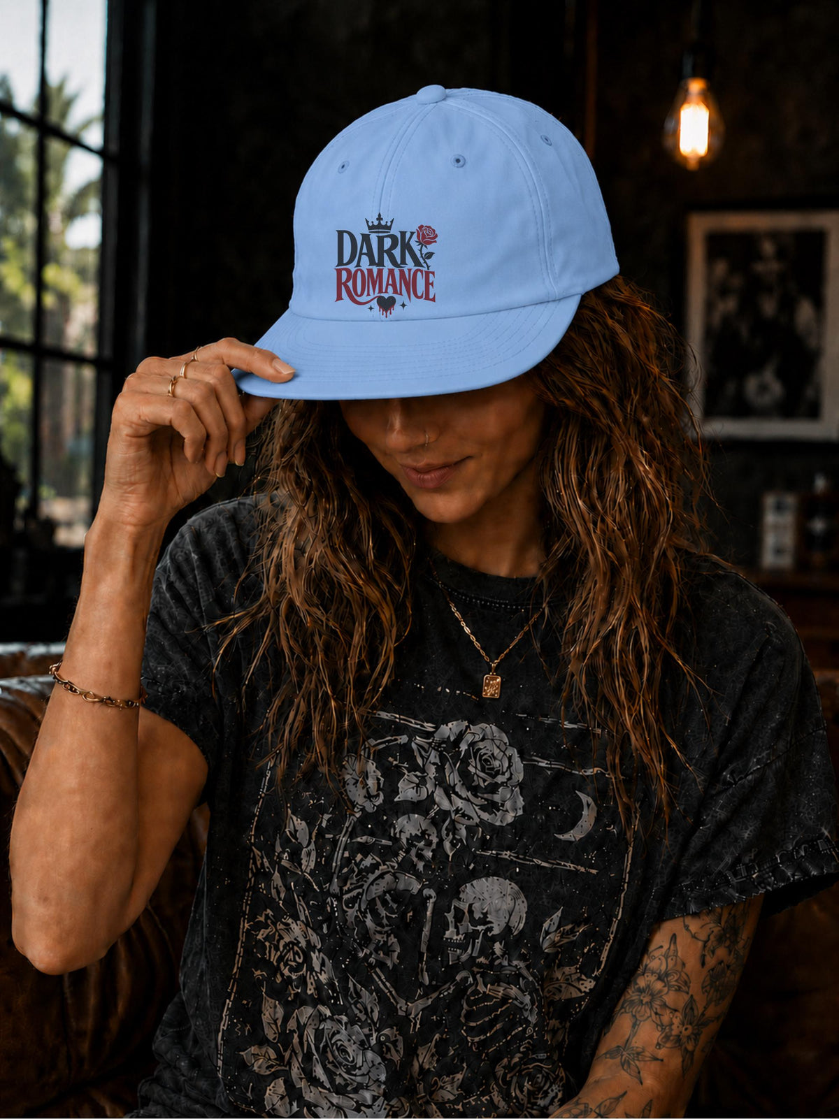 Woman wearing a surf cap featuring a Dark Romance graphic with red rose detail, photographed in a moody bookish setting with dark academia aesthetic.
