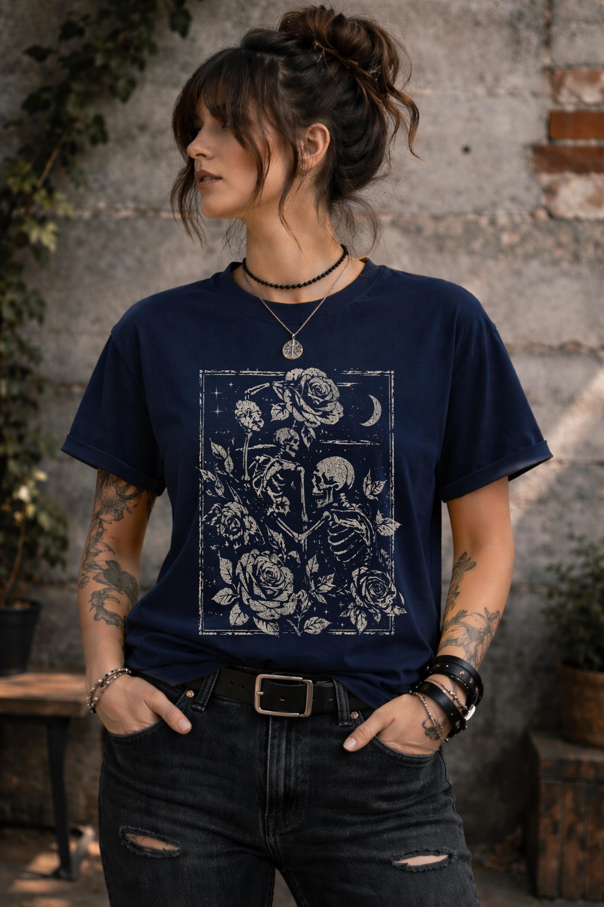 Woman wearing a graphic t-shirt featuring two skeleton lovers surrounded by roses beneath a crescent moon in a gothic dark academia style design.
