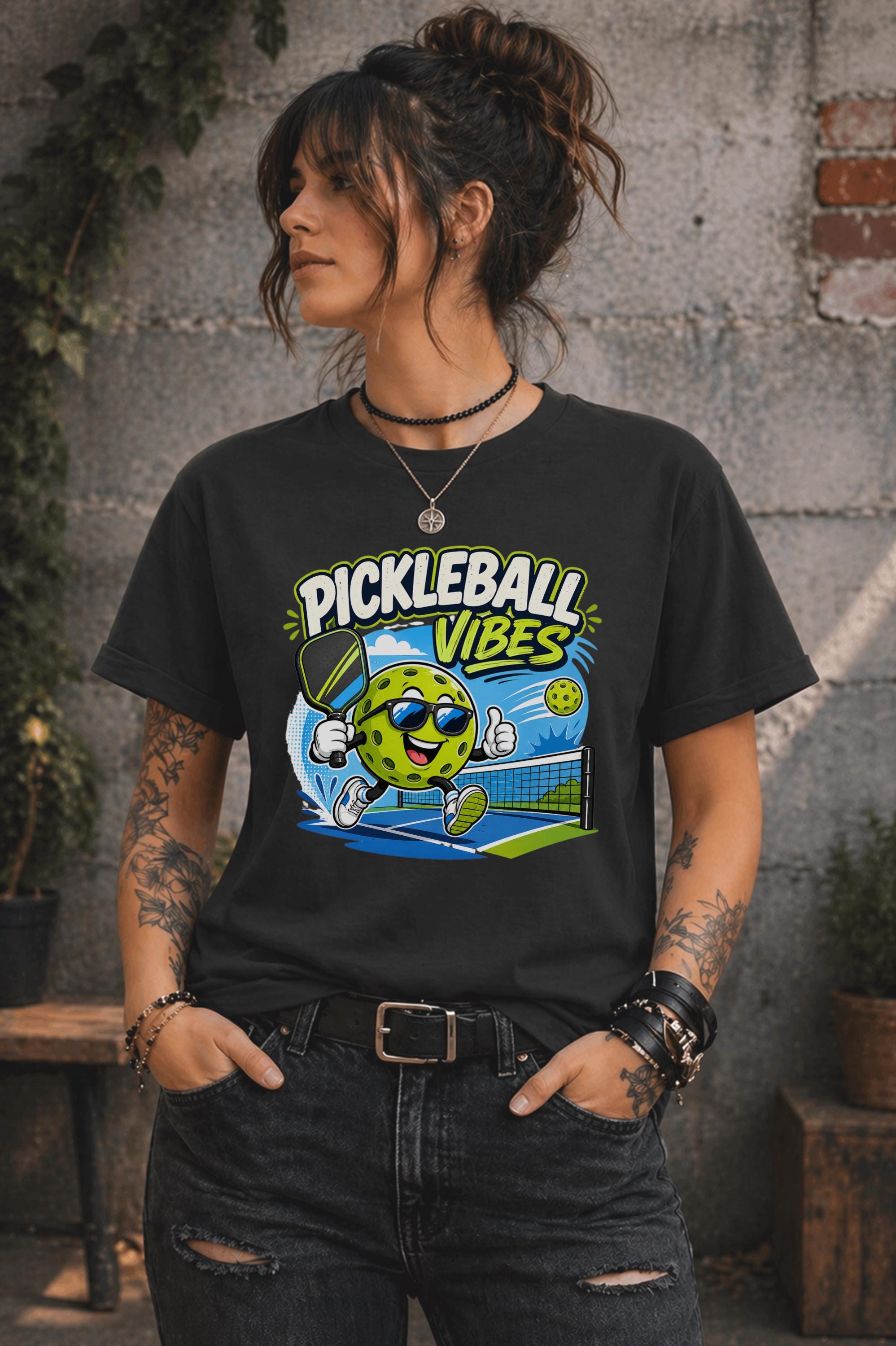 Woman wearing a Pickleball Vibes graphic t-shirt featuring a smiling pickleball character with sunglasses, paddle artwork, and colorful court-themed design.