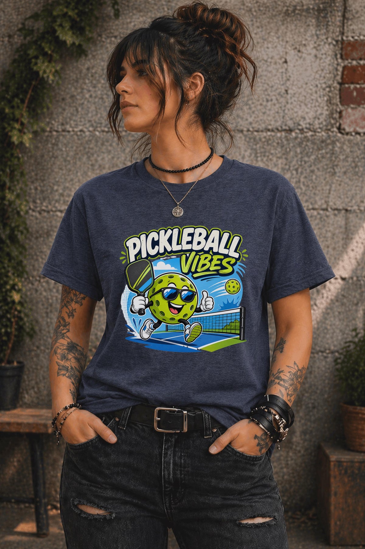 Woman wearing a Pickleball Vibes graphic t-shirt featuring a smiling pickleball character with sunglasses, paddle artwork, and colorful court-themed design.