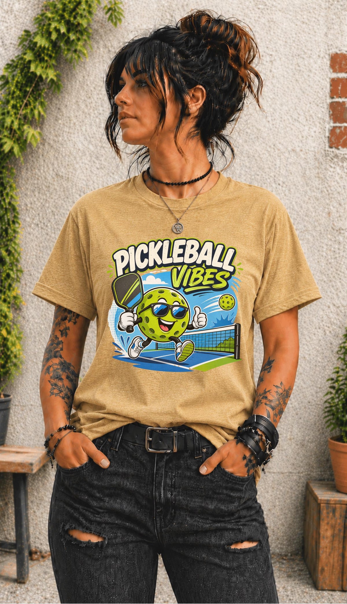 Woman wearing a Pickleball Vibes graphic t-shirt featuring a smiling pickleball character with sunglasses, paddle artwork, and colorful court-themed design.