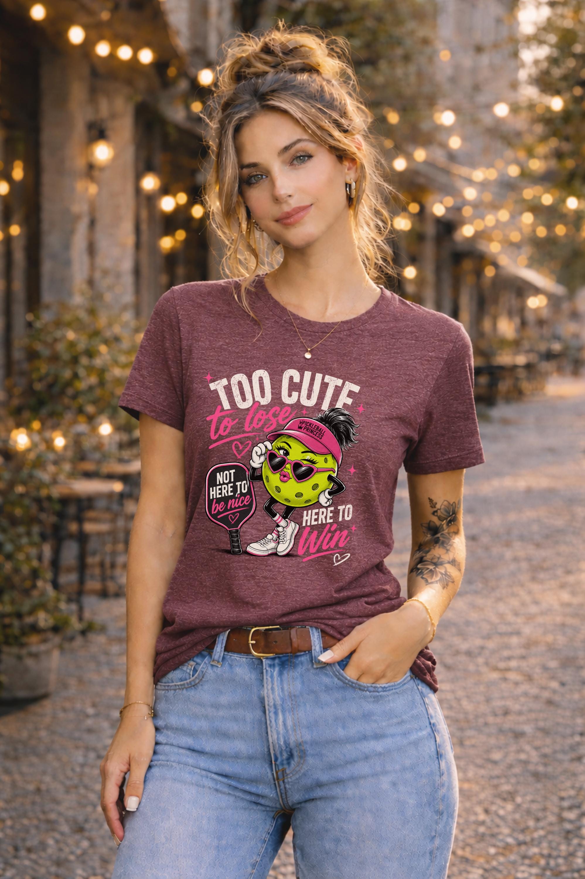 Woman wearing a Too Cute To Lose pickleball graphic t-shirt featuring a stylish pickleball character with heart sunglasses, pink visor, paddle artwork, and playful court-inspired design.