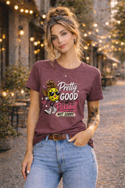 Woman wearing a pickleball graphic t-shirt featuring a stylish pickleball character with sunglasses, leopard-print bow, and the phrase "Pretty Good At Pickleball Not Sorry" in pink and white lettering.