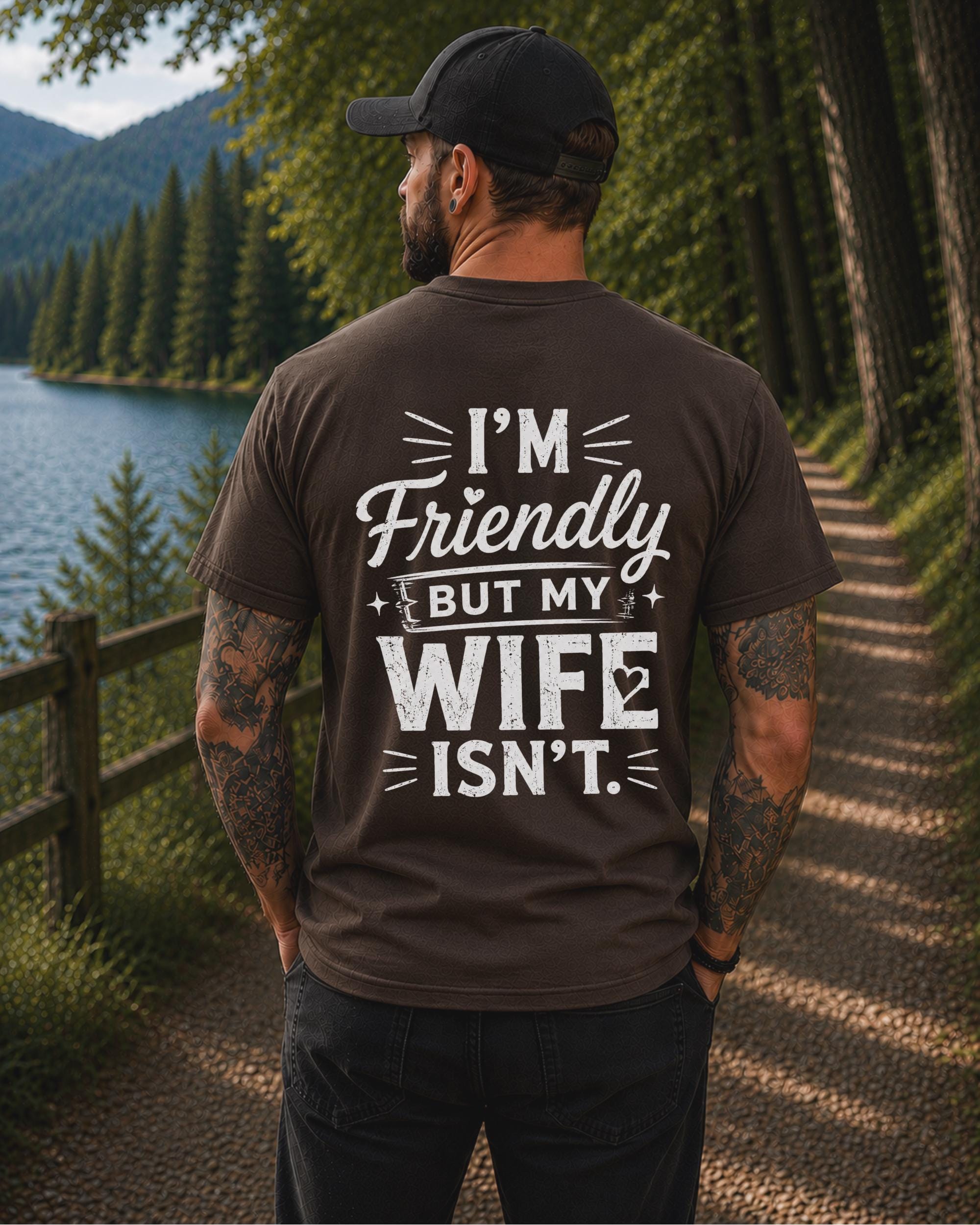 Back view of a black shirt featuring the humorous phrase "I'm Friendly But My Wife Isn't" in distressed white typography.