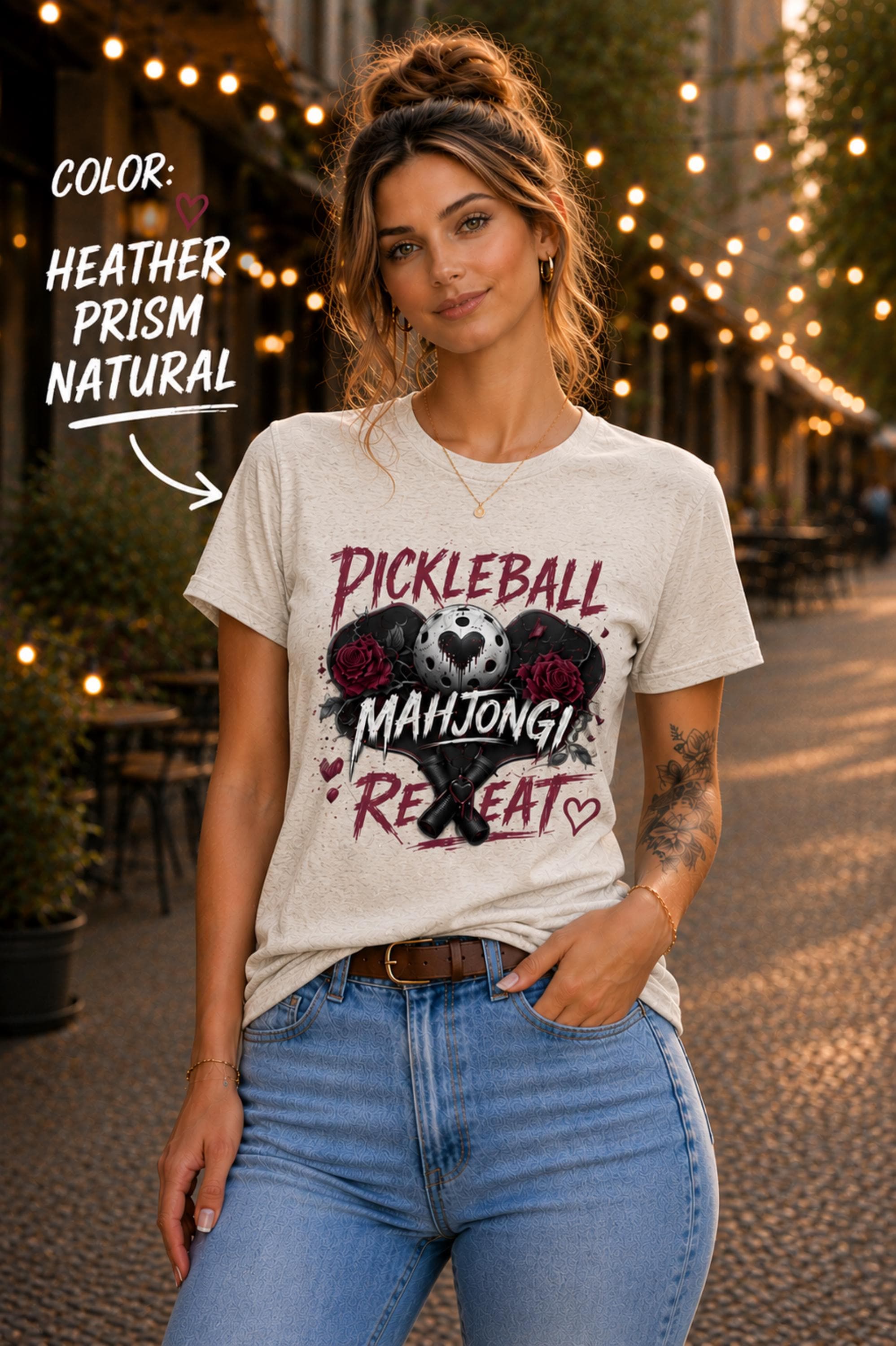 short-sleeve t-shirt featuring a graphic print with the text "PICKLEBALL MAHJONG REPEAT". The design includes a central pickleball with a heart cutout, flanked by two red roses, and two crossed pickleball paddles below.