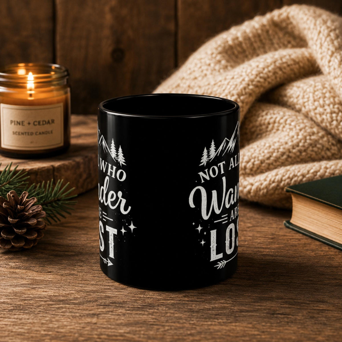 The front of the Black ceramic mug featuring mountain artwork and the phrase "Not All Who Wander Are Lost" displayed in white typography on a cozy rustic background.