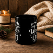 The front of the Black ceramic mug featuring mountain artwork and the phrase "Not All Who Wander Are Lost" displayed in white typography on a cozy rustic background.