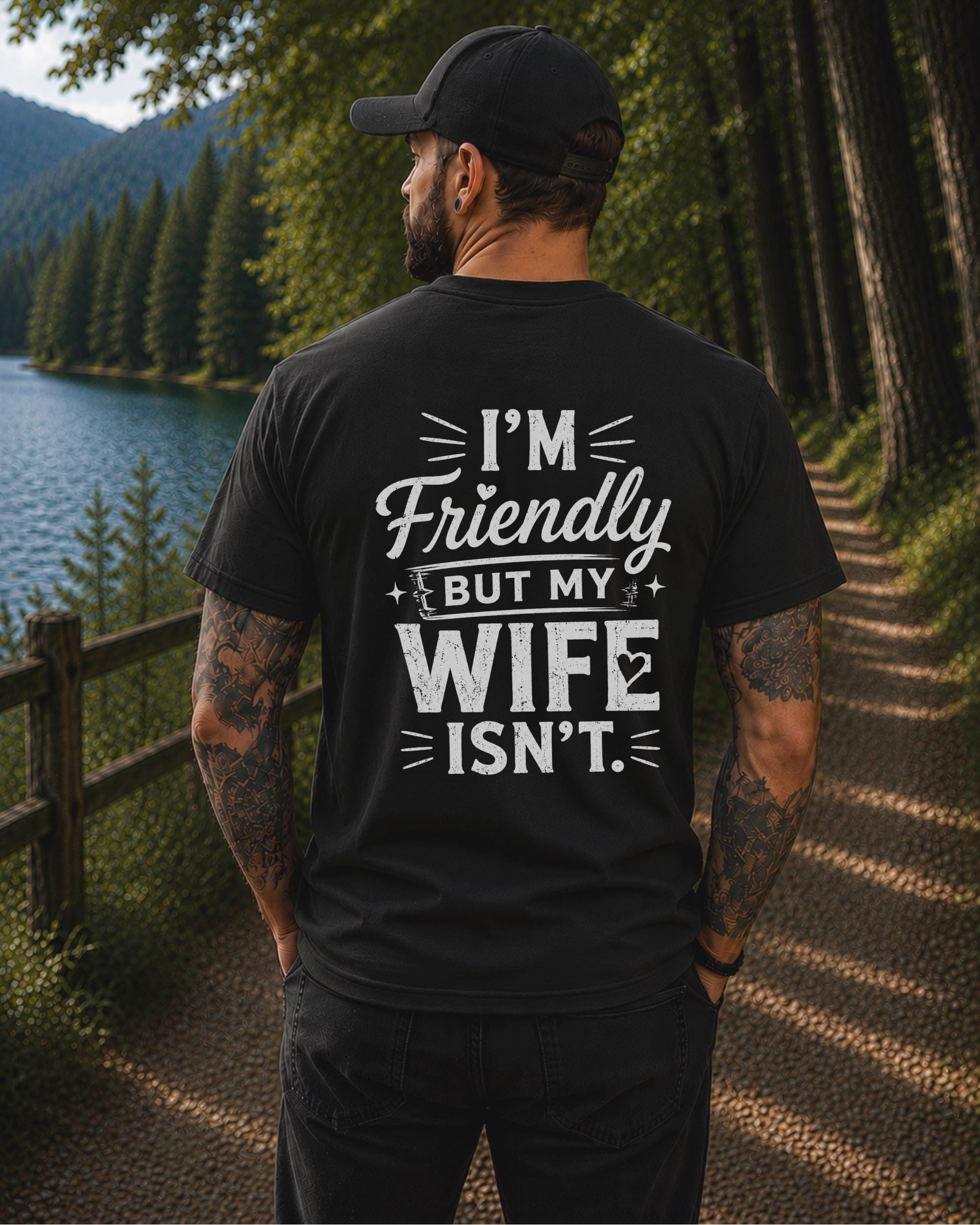 Back view of a black shirt featuring the humorous phrase "I'm Friendly But My Wife Isn't" in distressed white typography.