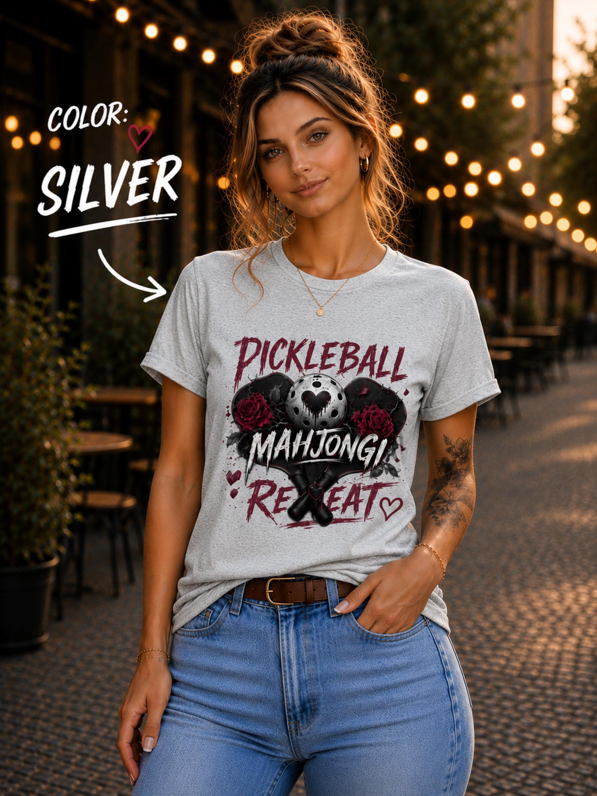 short-sleeve t-shirt featuring a graphic print with the text "PICKLEBALL MAHJONG REPEAT". The design includes a central pickleball with a heart cutout, flanked by two red roses, and two crossed pickleball paddles below.