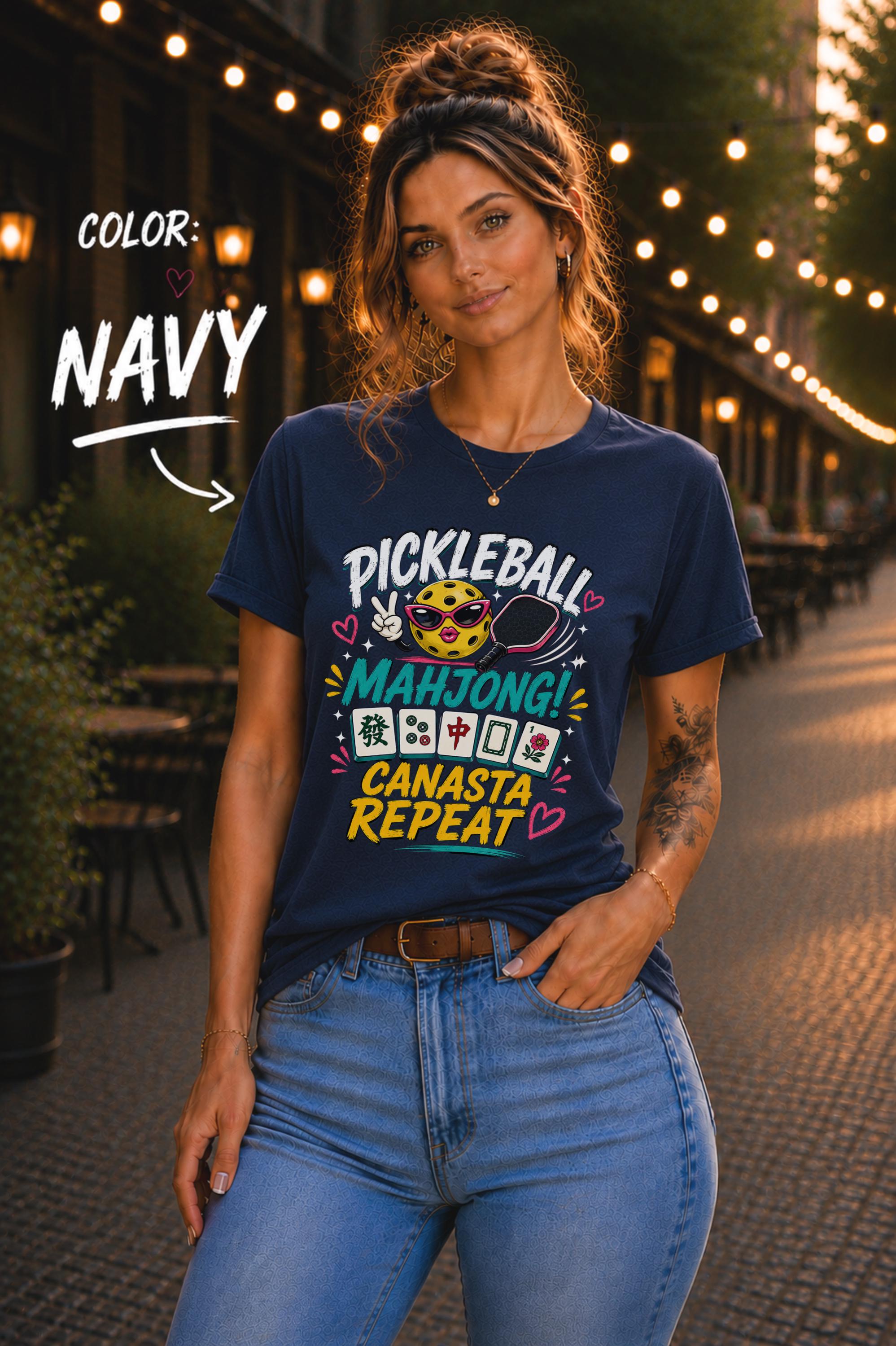 Woman wearing a navy graphic t-shirt featuring the colorful phrase "Pickleball Mahjong Canasta Repeat" with a smiling pickleball character, paddle, and Mahjong tiles, styled for casual everyday wear.