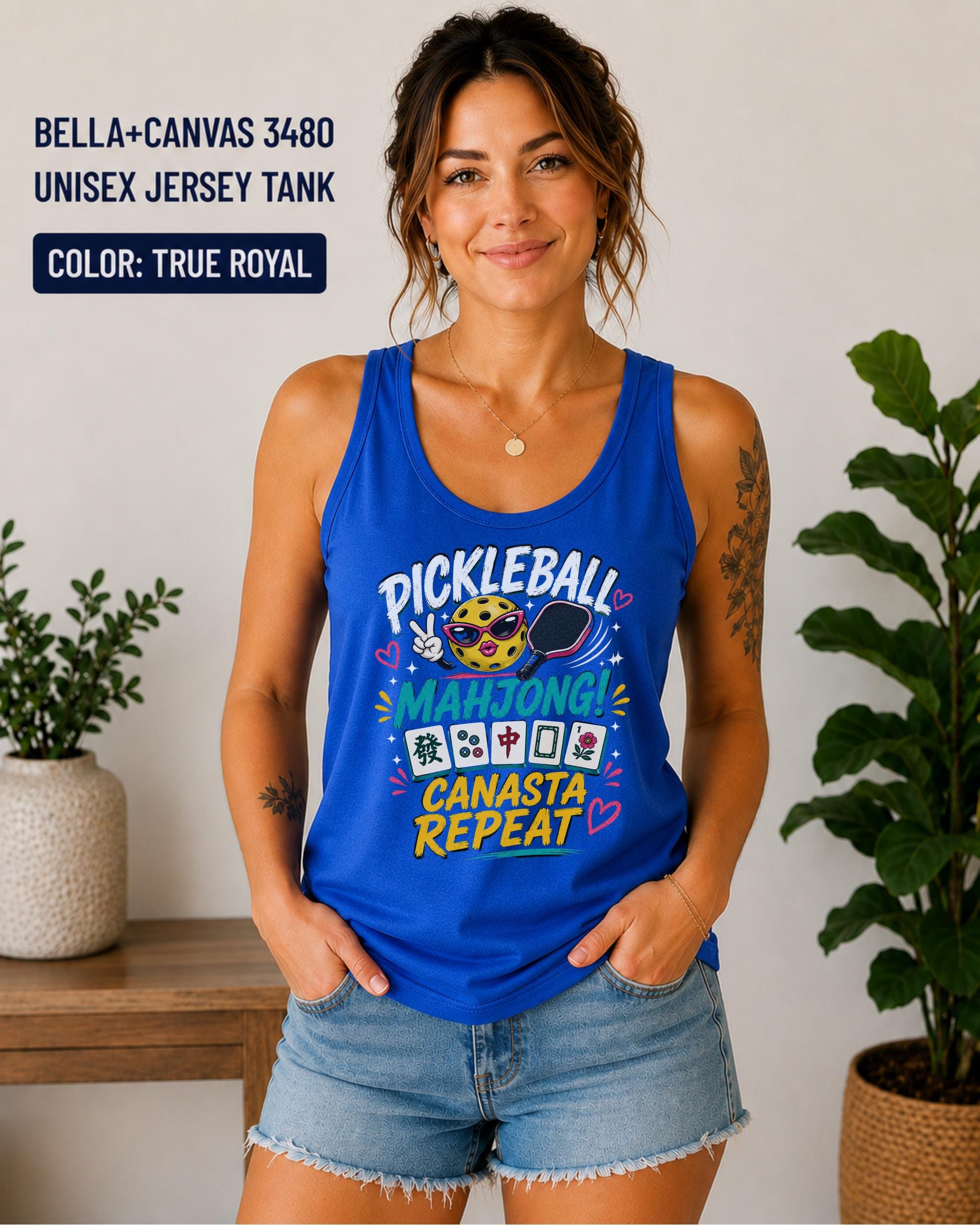 Woman wearing a true royal Bella+Canvas 3480 jersey tank featuring a colorful "Pickleball Mahjong Canasta Repeat" graphic with a smiling pickleball character, paddle, and Mahjong tiles.