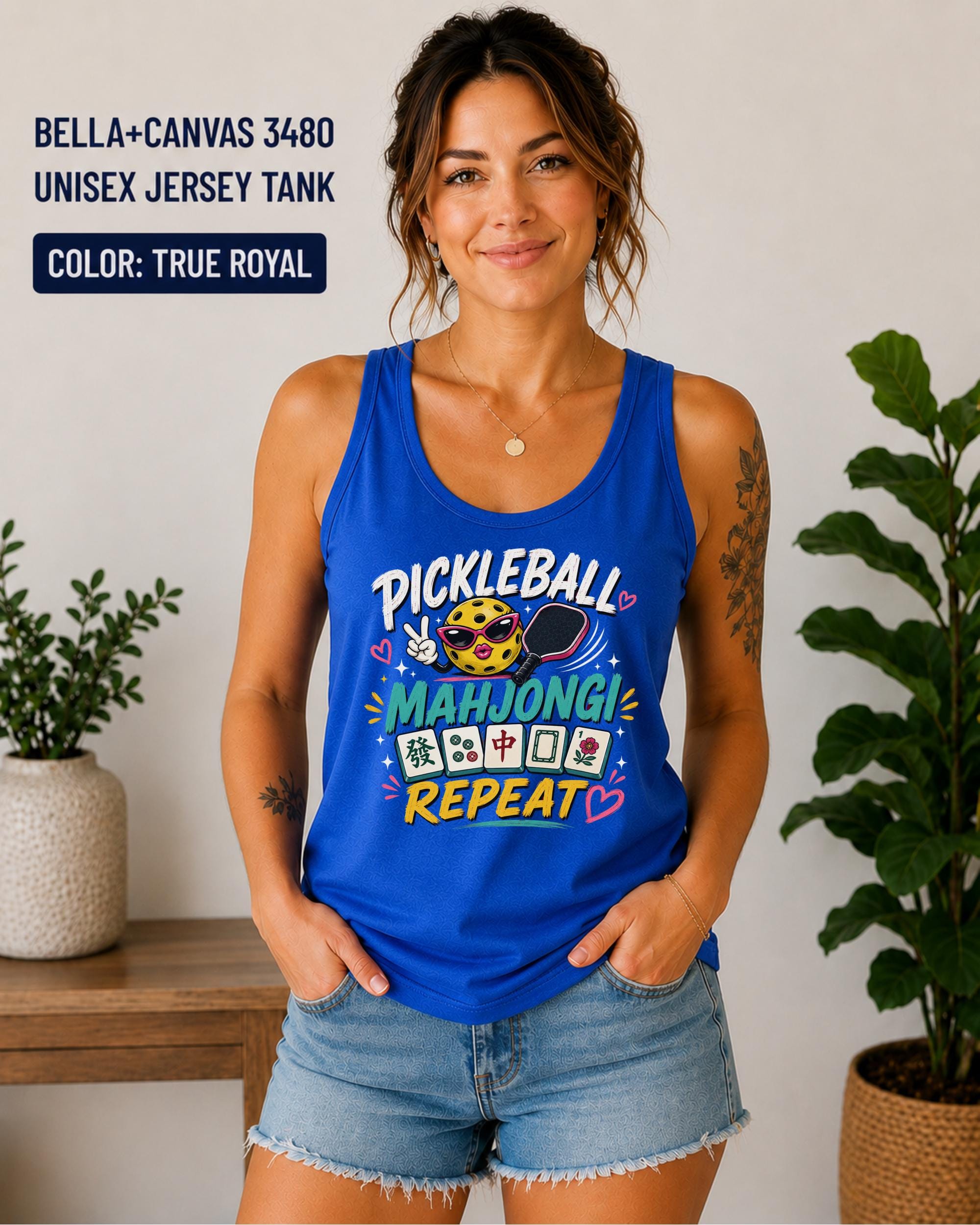 Woman wearing a true royal Bella+Canvas 3480 unisex jersey tank featuring a colorful "Pickleball Mahjong Repeat" graphic with a smiling pickleball, paddle, Mahjong tiles, and bright playful lettering.