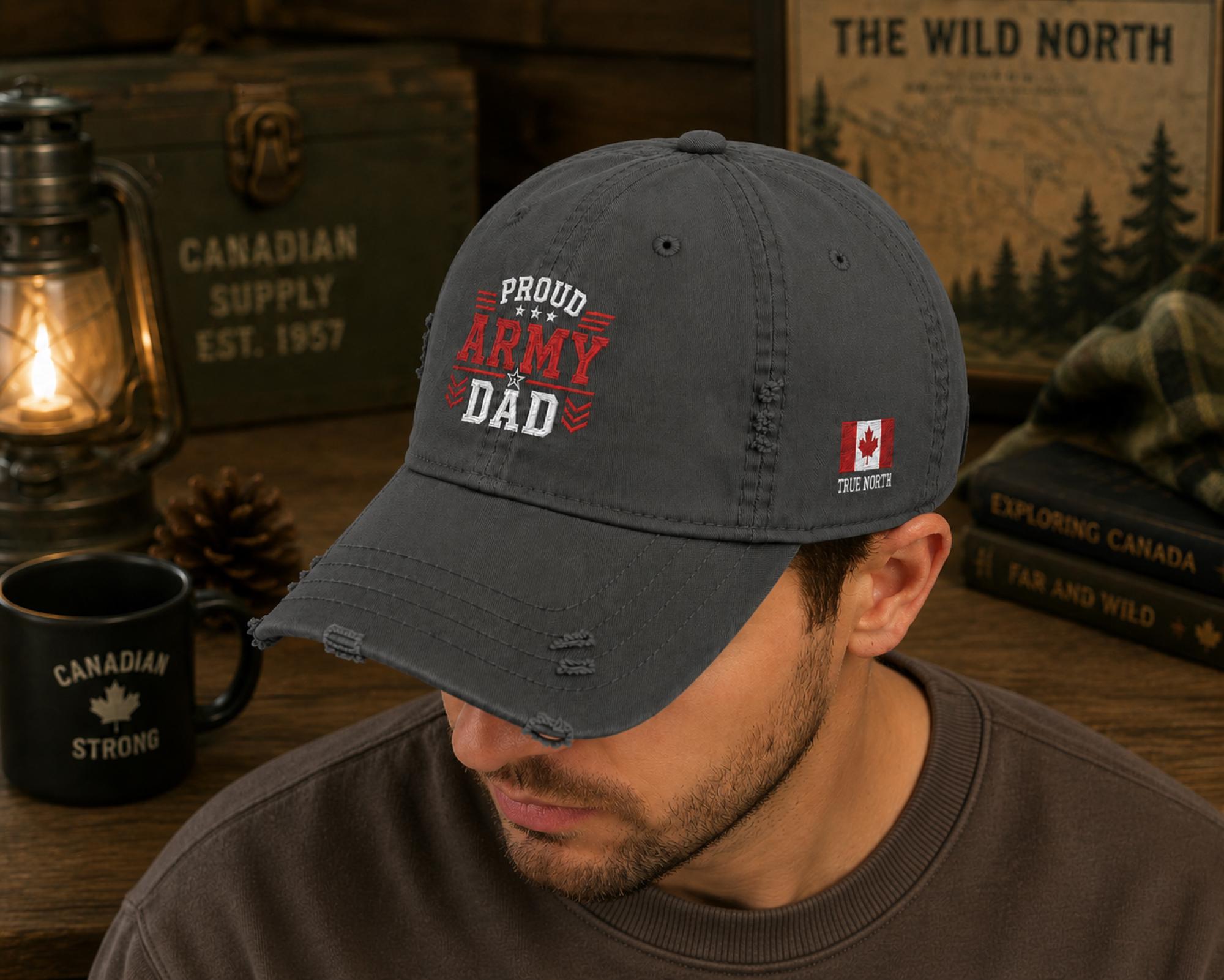Charcoal distressed embroidered dad hat featuring a bold "Proud Army Dad" design on the front with a red maple leaf and "EH!" embroidery on the side, styled in a rustic outdoor setting with camping accessories.
