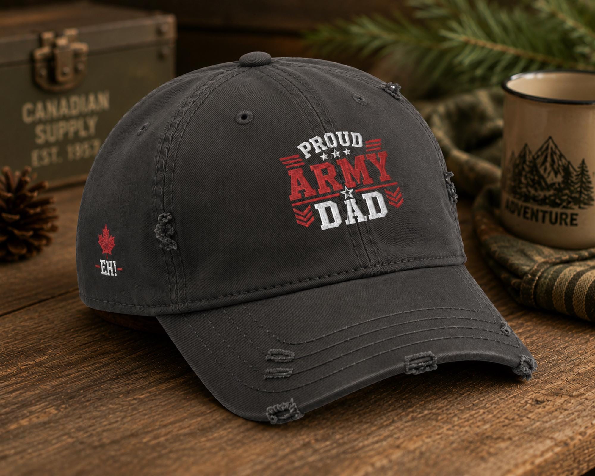 Charcoal distressed embroidered dad hat featuring a bold "Proud Army Dad" design on the front with a red maple leaf and "EH!" embroidery on the side, styled in a rustic outdoor setting with camping accessories.