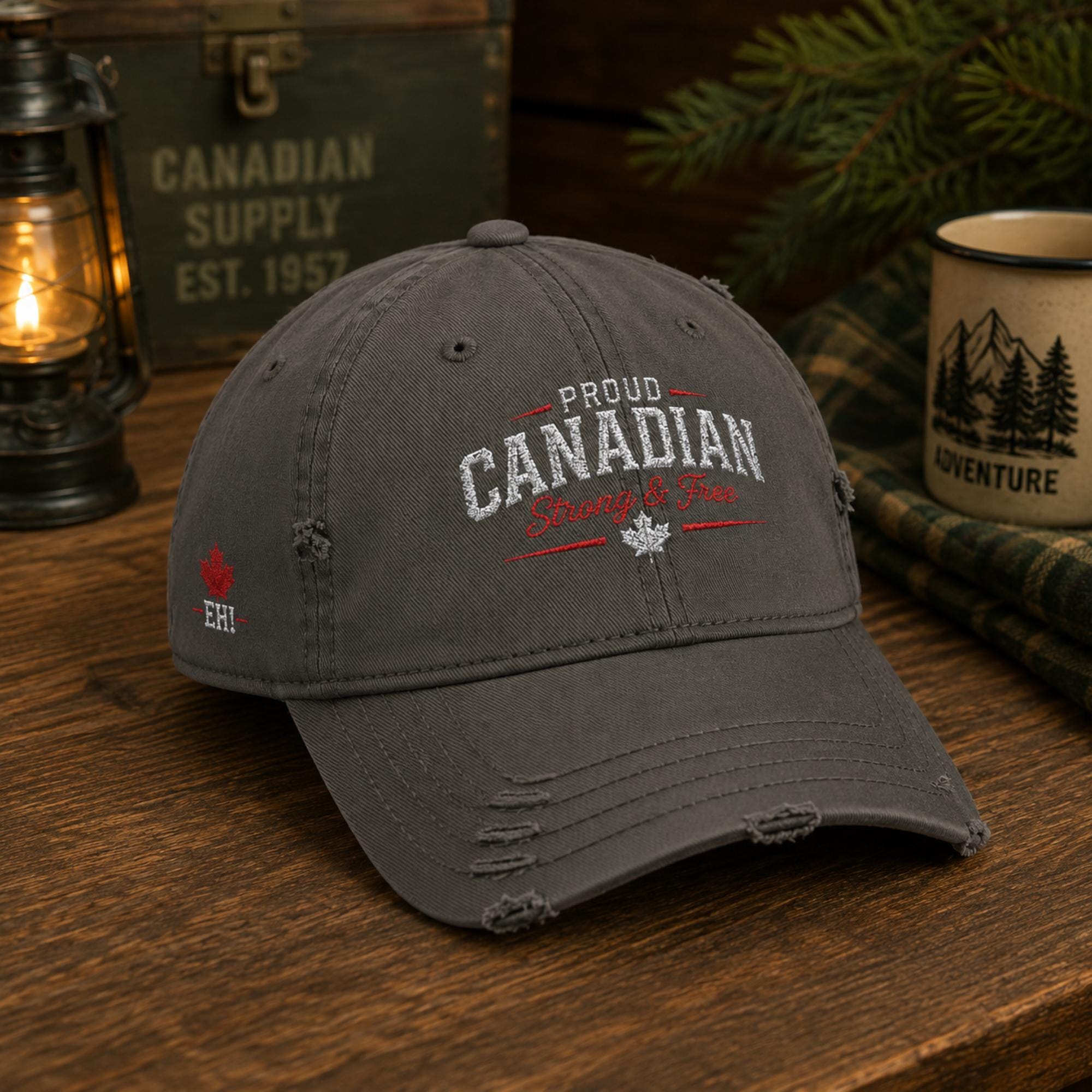 Charcoal distressed embroidered dad hat featuring "Proud Canadian Strong & Free" on the front with maple leaf accents, Canadian flag embroidery on the side, and an EH! maple leaf detail in a rustic outdoor setting.