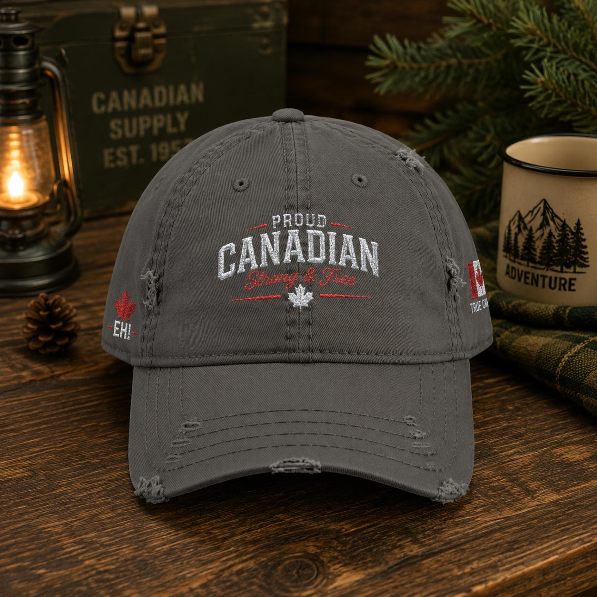Charcoal distressed embroidered dad hat featuring "Proud Canadian Strong & Free" on the front with maple leaf accents, Canadian flag embroidery on the side, and an EH! maple leaf detail in a rustic outdoor setting.