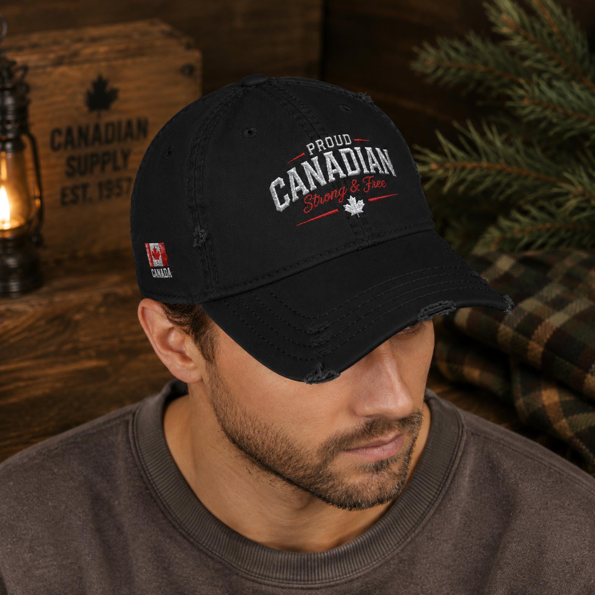Black distressed embroidered dad hat featuring "Proud Canadian Strong & Free" on the front with maple leaf accents, Canadian flag embroidery on the side, and an EH! maple leaf detail in a rustic outdoor setting.