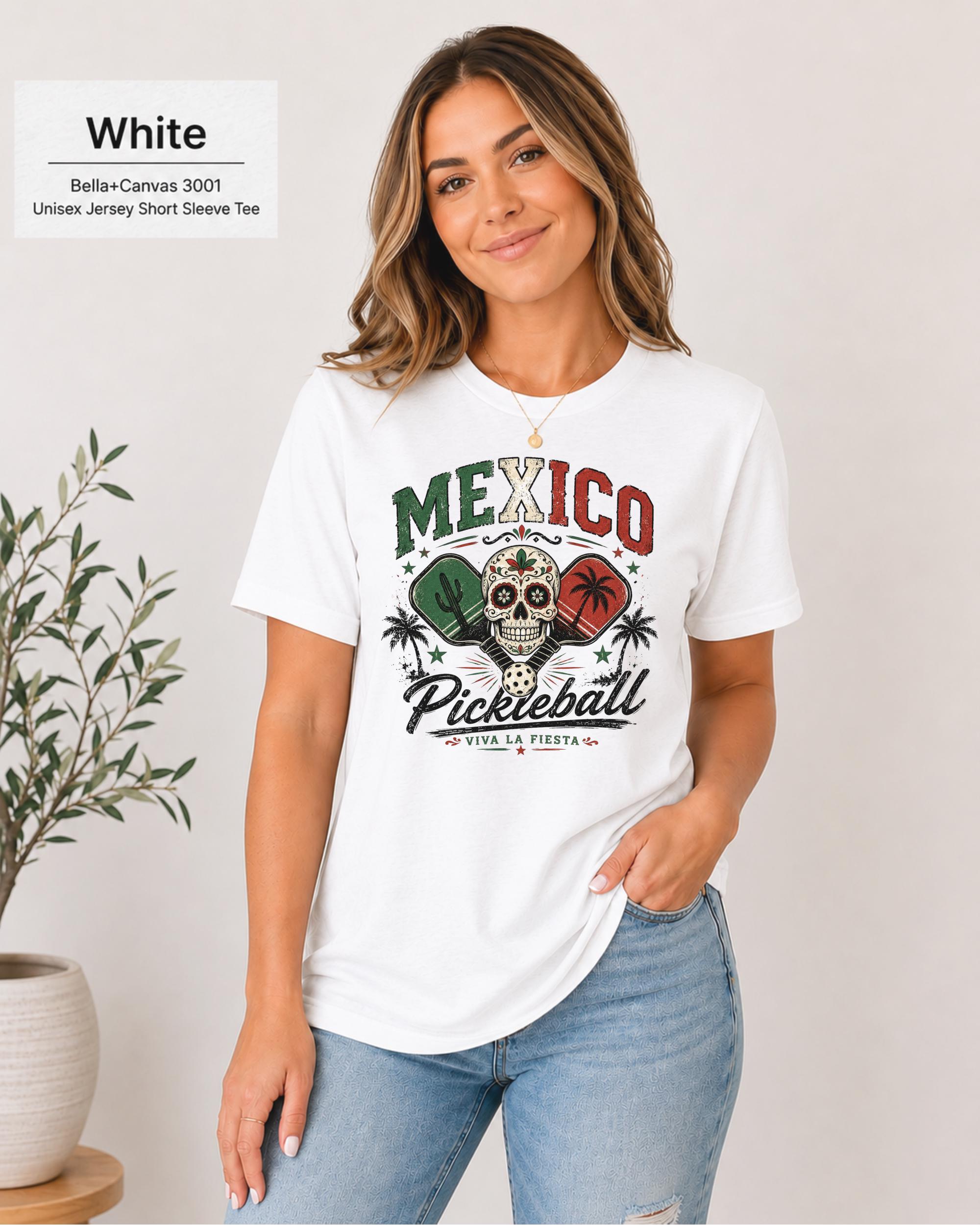 Woman wearing a White Bella+Canvas 3001 T-shirt featuring a colorful Mexico Pickleball sugar skull design with cactus, paddles, palm trees, and "Viva La Fiesta" text.