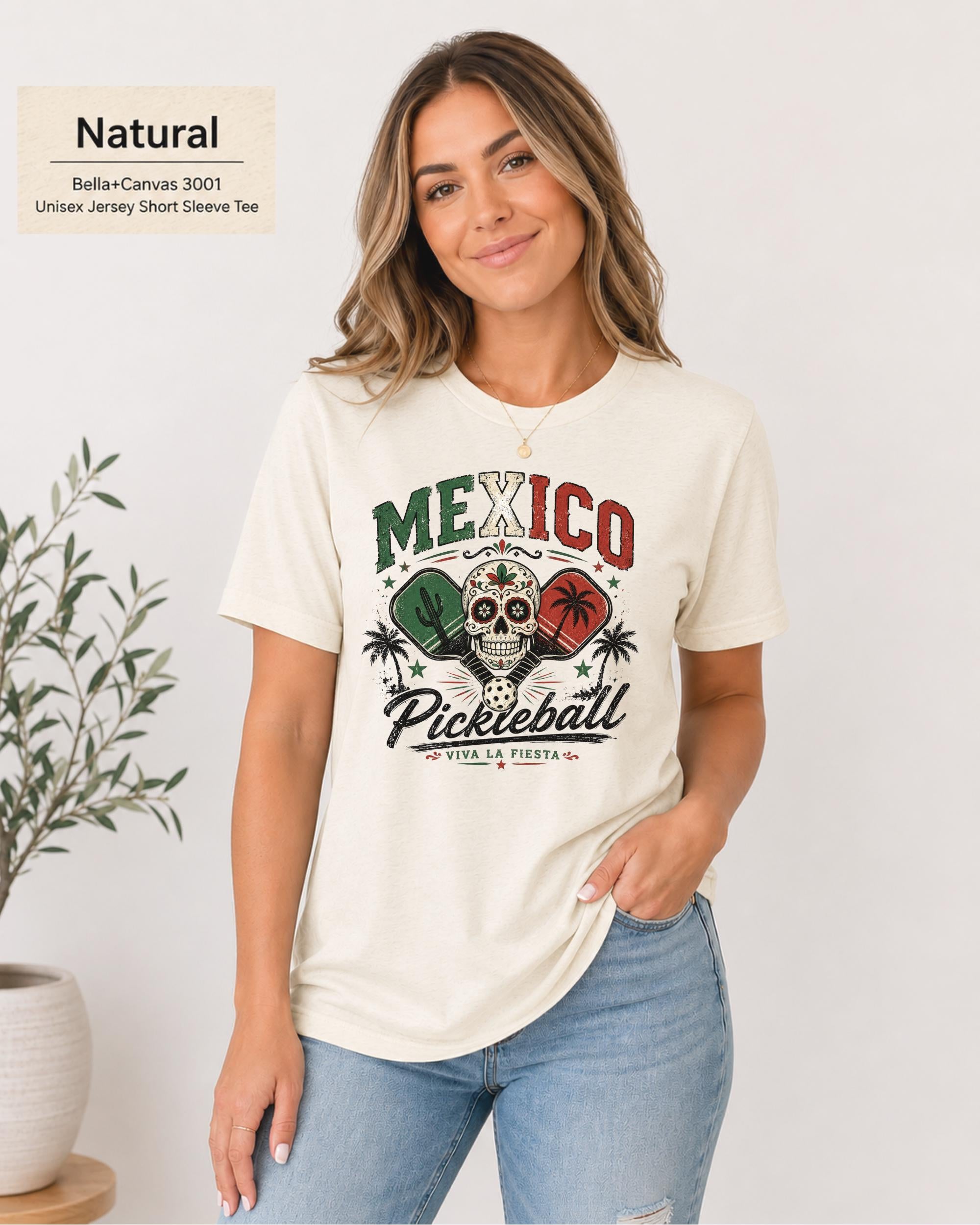Woman wearing a Natural Bella+Canvas 3001 T-shirt featuring a colorful Mexico Pickleball sugar skull design with cactus, paddles, palm trees, and "Viva La Fiesta" text.